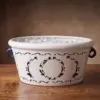 Champanera de cerámica blanca pintada a mano con asas azules, llena de hielo, sobre una mesa de madera